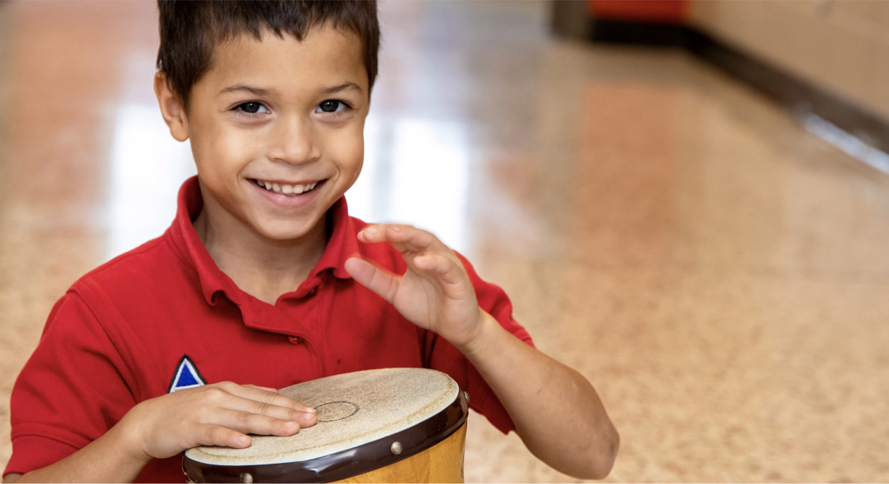 A boy sitting and playing the bongos